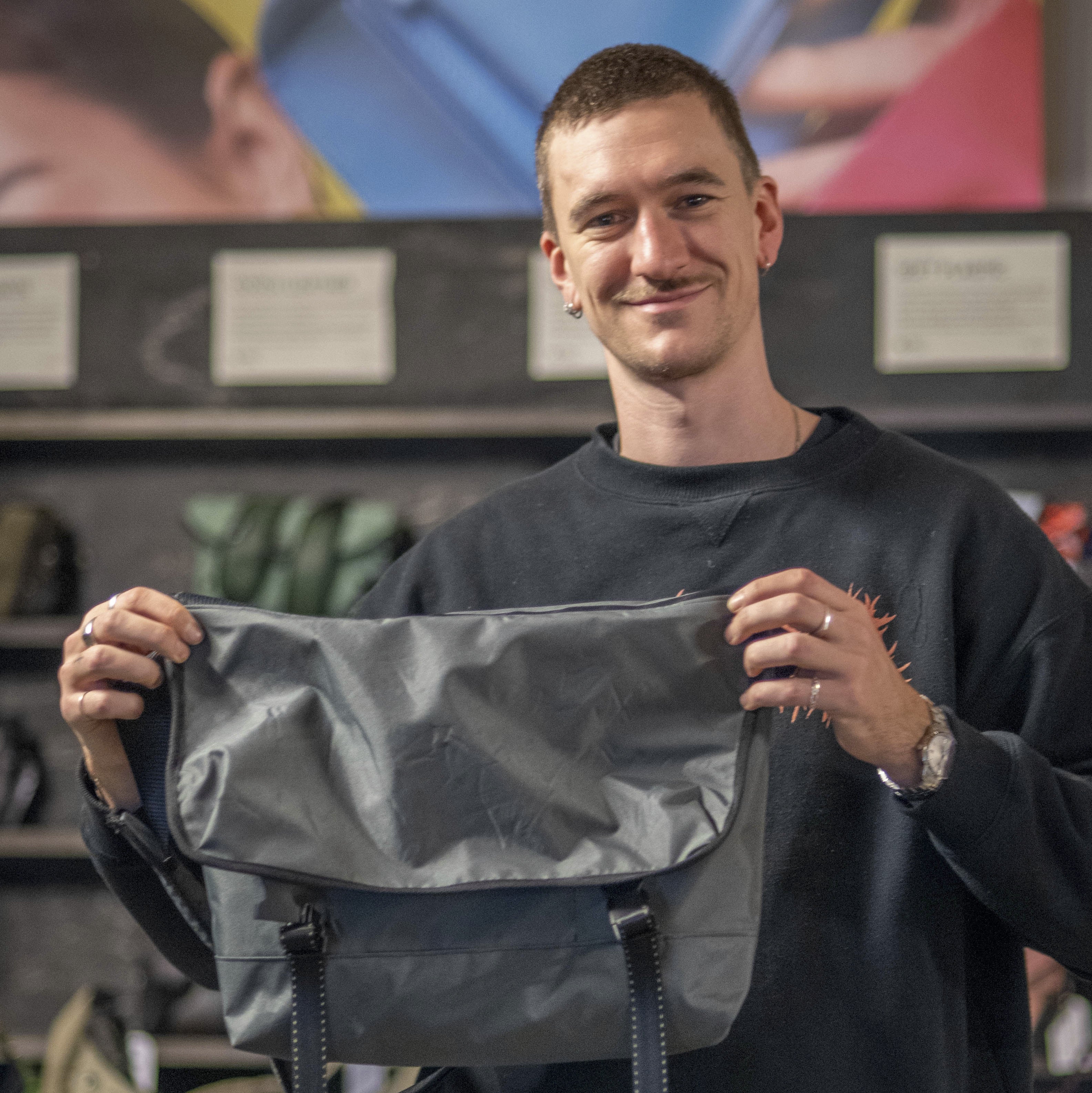 Man holding a gray bag in a store setting