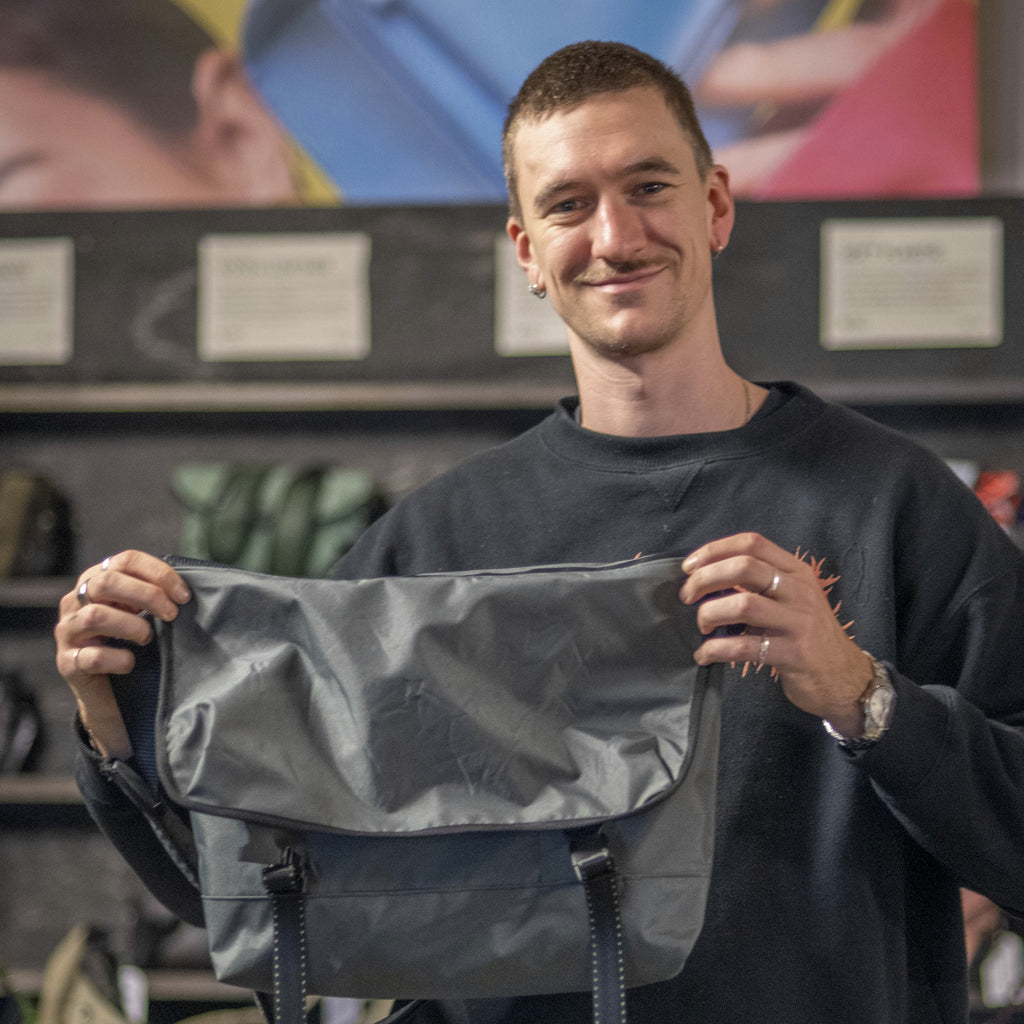Man holding a gray bag in a store setting