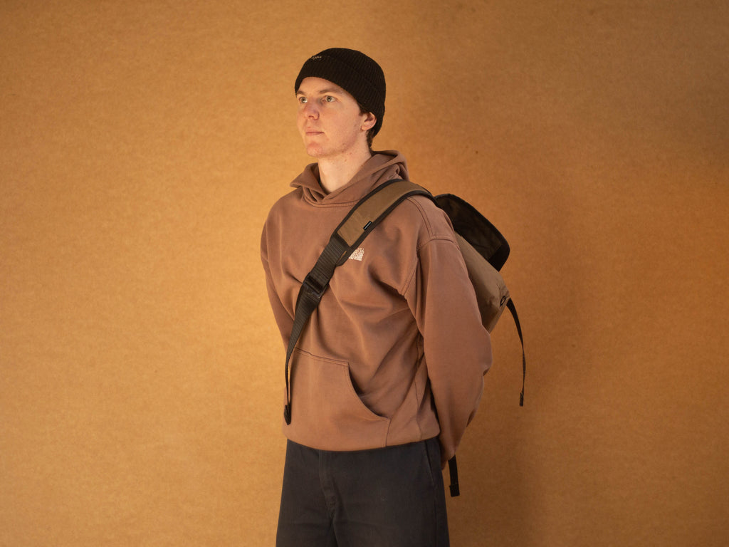 Side view of person wearing wipwrk Mondo messenger bag in green slung across the body with adjustable padded shoulder strap demonstrating on-body fit